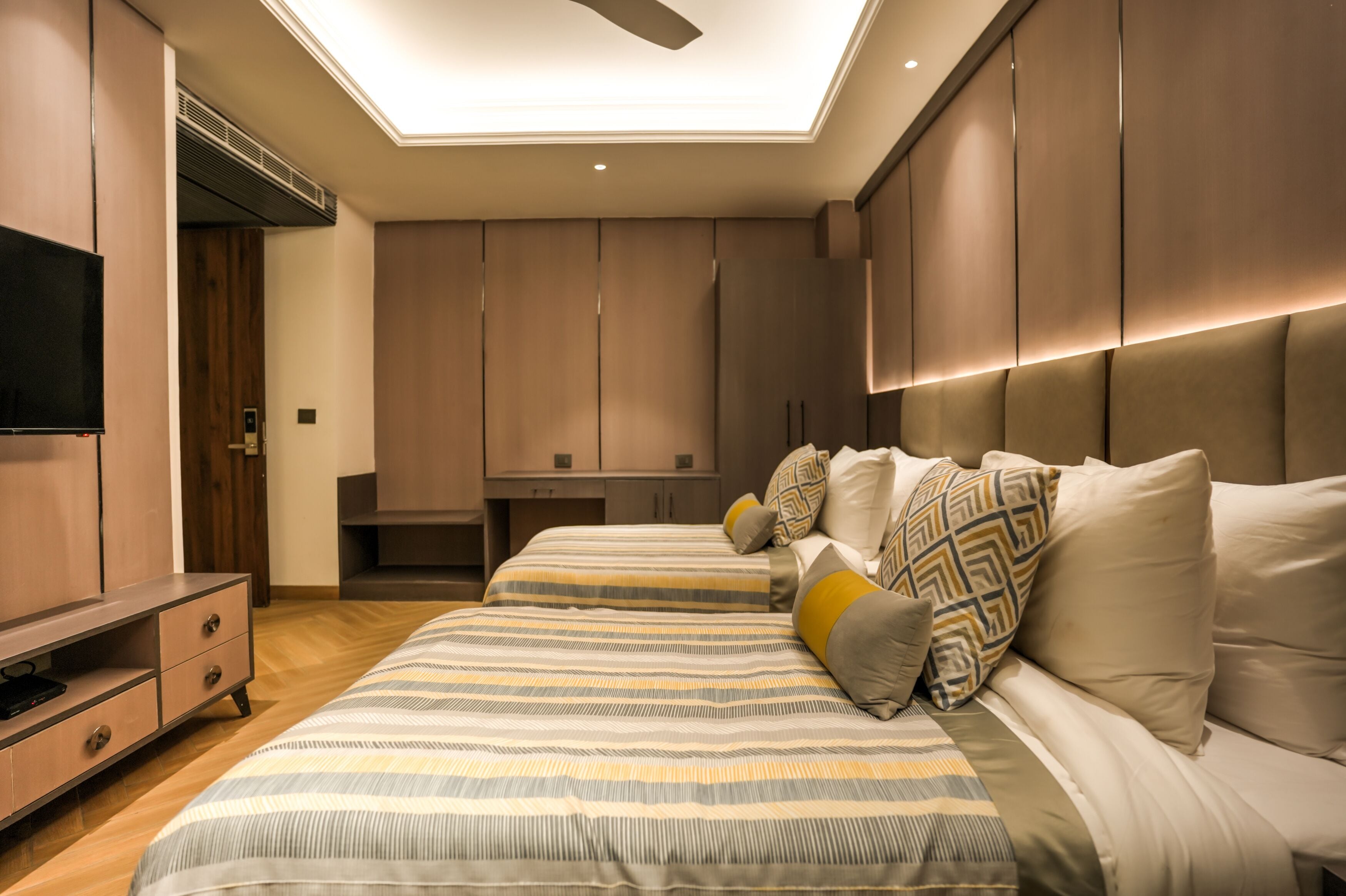 A modern bedroom with a large bed, a TV, and built-in cabinets.
