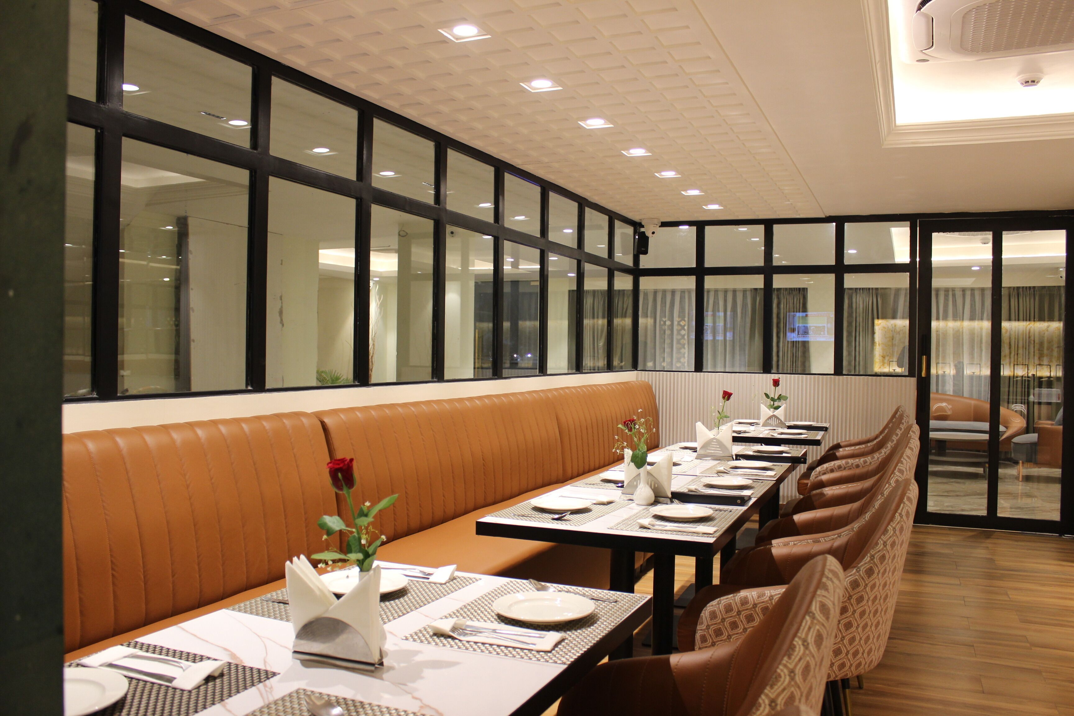 Un restaurant doté d’une longue table dressée pour le dîner, d’un espace avec des banquettes et de grandes fenêtres offrant une vue panoramique.