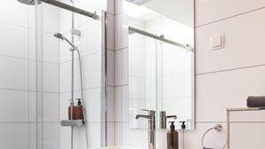 A modern bathroom with a glass shower enclosure, white vanity, and a large mirror. - Garden View (Double or Twin) (Overschild)