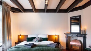 A bedroom with a bed, two bedside lamps, a fireplace, and a large mirror above it. - Garden View (Double or Twin) (Overschild)