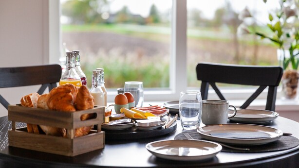 A breakfast table with croissants, eggs, and juice bottles, set against a view of a green landscape. - Garden View (Double or Twin) (Overschild)