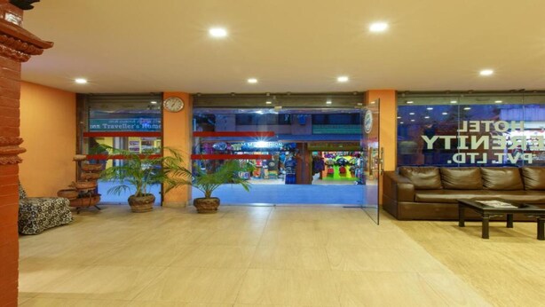 A hotel lobby with a reception desk, seating area, and a view of the street. - MeroStay 167 Serenity (Kathmandu)