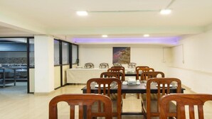 A dining area with a long table, wooden chairs, and a painting on the wall. - MeroStay 167 Serenity (Kathmandu)