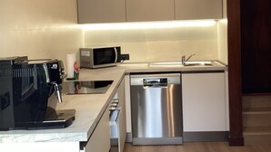 Eine moderne Küche mit weißen Schränken, einer eingebauten Mikrowelle, einer Kaffeemaschine und einem Geschirrspüler.