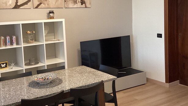Ein modernes Wohnzimmer mit Essbereich, Fernseher und Kunstwerken an der Wand.