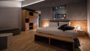 A modern bedroom with a large bed, wooden wardrobe, and bedside lamps. - Bach Boutique Hotel (Sappada)