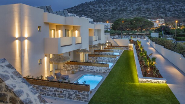 A modern hotel with a pool, outdoor seating, and a view of the surrounding landscape.