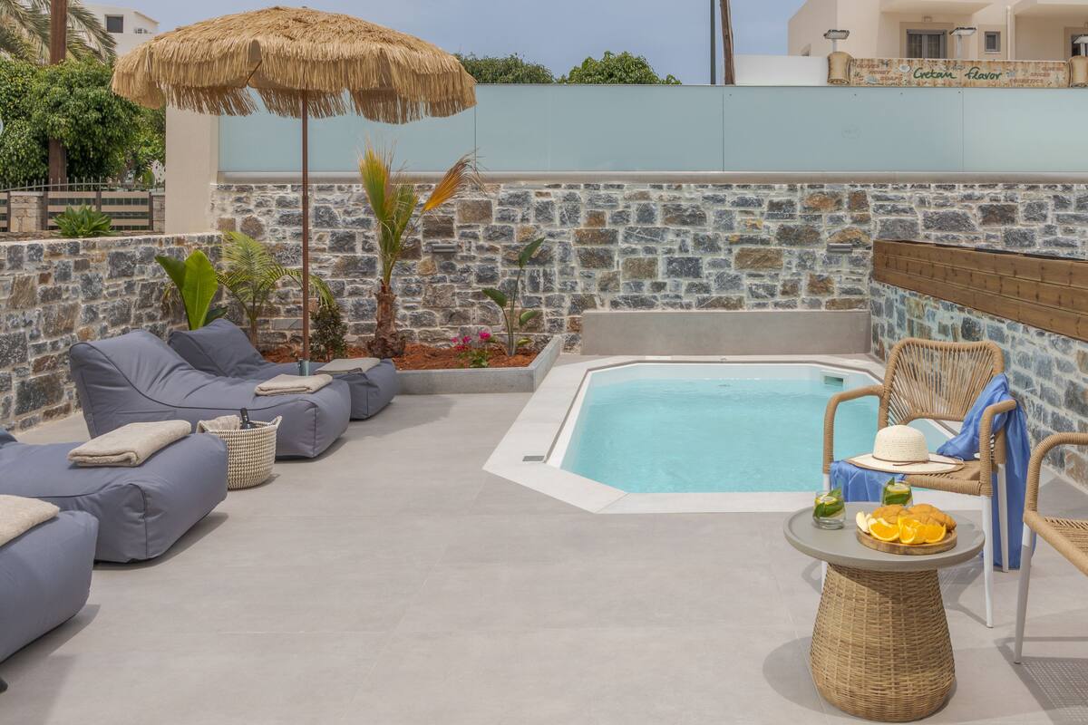 A poolside area with a stone wall, a hot tub, and lounge seating.