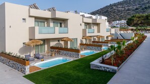A modern hotel with a swimming pool, outdoor seating, and a view of a mountainous landscape.
