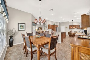 A spacious kitchen with modern appliances, a dining area with a wooden table and chairs, and a central island with bar stools. - Willie’s Place w/Golf Cart, Hot Tub & Dog Friendly (The Villages)