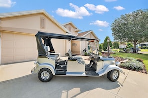 A vintage golf cart parked in front of a residential garage. - Willie’s Place w/Golf Cart, Hot Tub & Dog Friendly (The Villages)