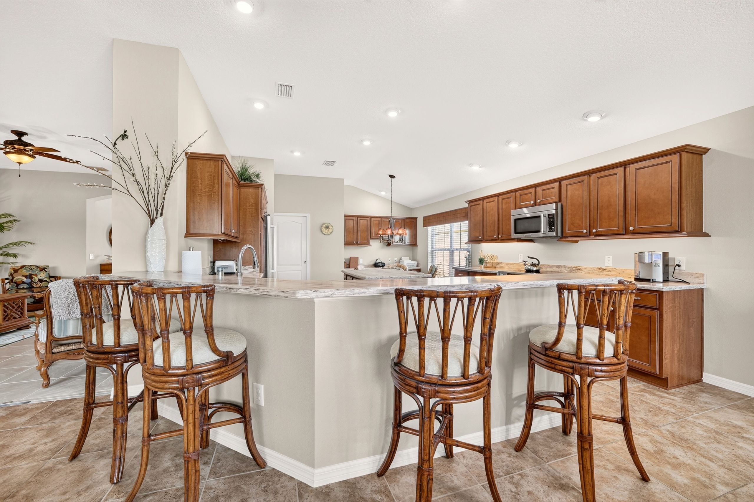 Cocina amplia con una isla central, armarios de madera y un microondas moderno.