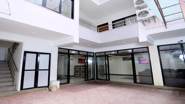 A hotel lobby with a staircase, glass doors, and an air conditioning unit. - MeroStay 184 Hotel Sweet Town (Kathmandu)