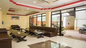 A lobby with a brown leather sofa, a brown armchair, and a glass coffee table. - MeroStay 184 Hotel Sweet Town (Kathmandu)