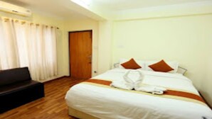 A hotel room with a bed, a bench, and a door. - MeroStay 184 Hotel Sweet Town (Kathmandu)
