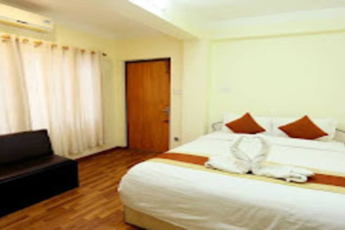 A hotel room with a bed, a bench, and a door.