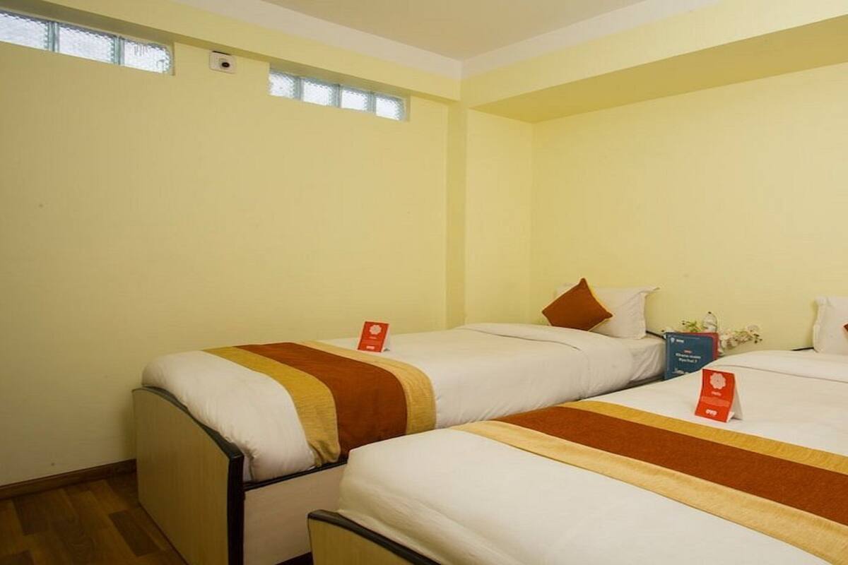 A hotel room with two single beds, each with a brown and white striped bedspread, and a small table with a red sign.