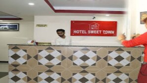 A reception desk with a sign reading "HOTEL SWEET TOWN" and a framed picture on the wall. - MeroStay 184 Hotel Sweet Town (Kathmandu)