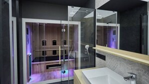 A modern bathroom with a glass-enclosed shower, a white sink, and a wooden vanity. - Apartamenty Swinoujscie -Matejki 1B (Swinoujscie)