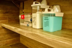 Une étagère avec des récipients étiquetés « Lessive en poudre » et « Adoucissant pour textiles ».