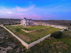 Une maison moderne à deux étages, entourée d’un mur en pierre.