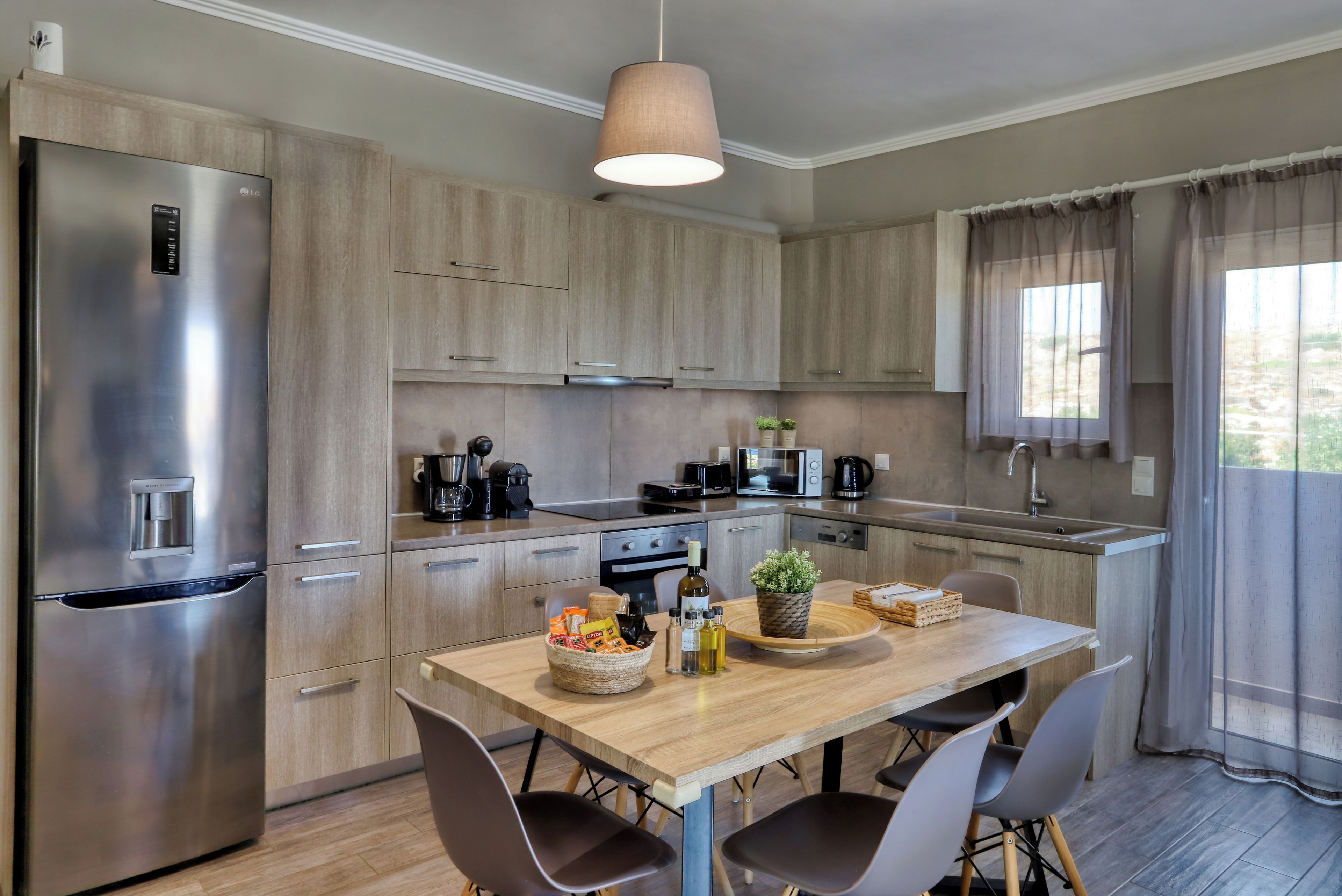 A modern kitchen with stainless steel appliances, wooden cabinets, a dining table with chairs, and a pendant light.