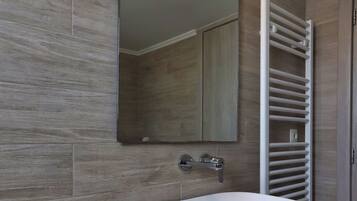 Un bagno con un lavabo a incasso, uno specchio, un portasciugamani e un porta carta igienica.