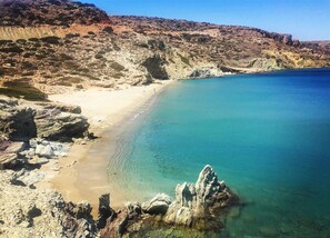 A coastal landscape with a sandy beach, clear blue waters, and rocky terrain. - Sitia Bay View Villa Apartment (Σητεία)