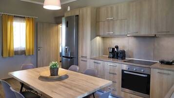 Een moderne keuken met houten kastjes, een inbouwoven en een eethoek met een tafel en stoelen.
