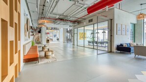 Un espacio de oficina moderno con un banco largo, un sofá y una zona de comedor con mesas.