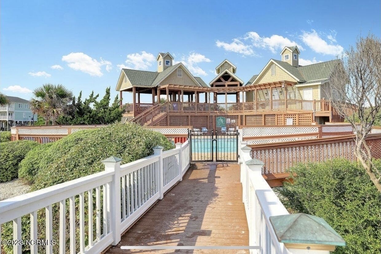 Um edifício grande, com vários andares, uma área de deck coberta e uma piscina.