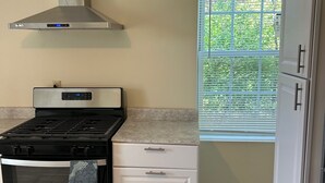 Una cocina con estufa, horno y ventana con persianas.
