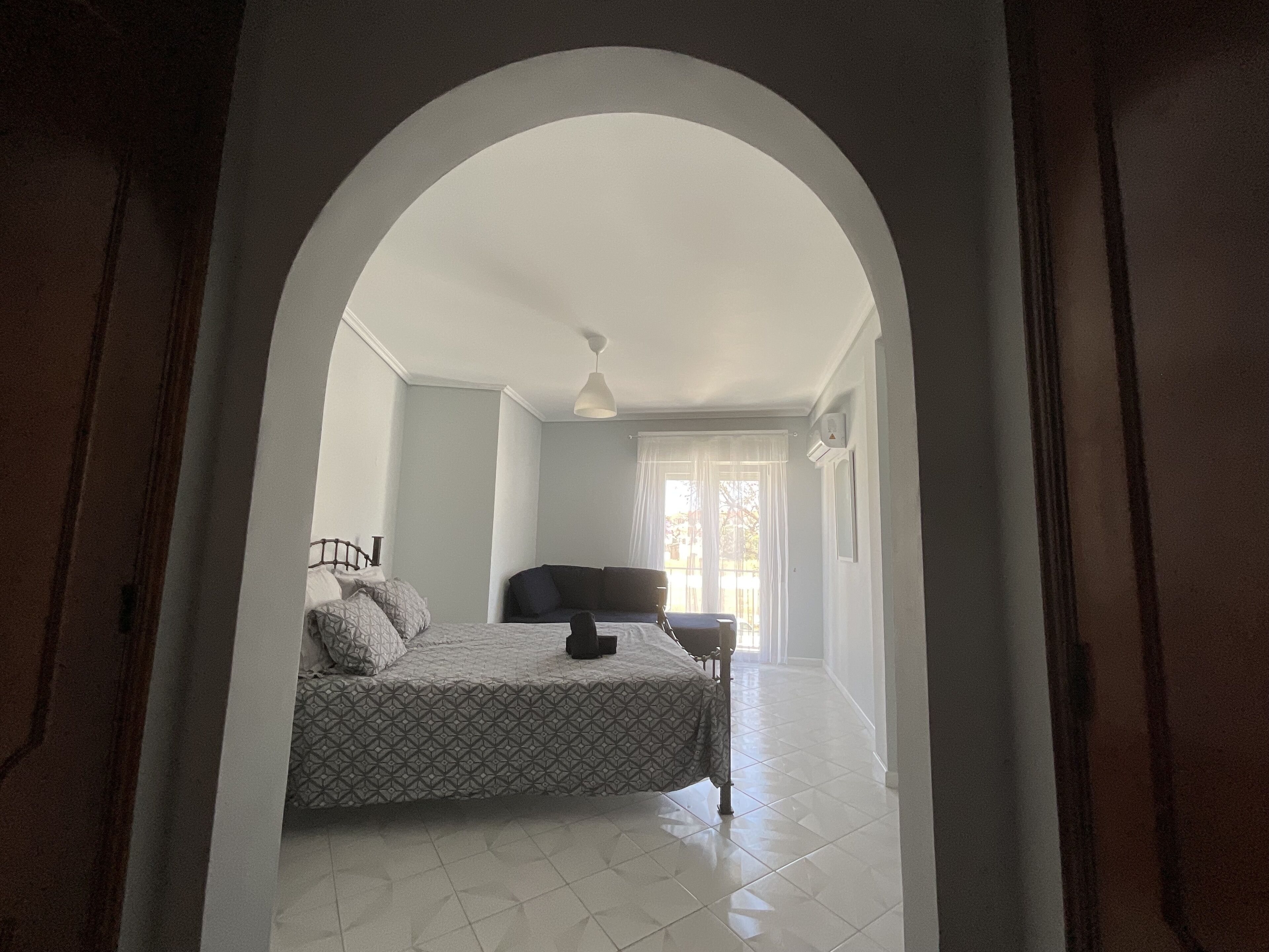 A bedroom with a bed, a chair, and a window.