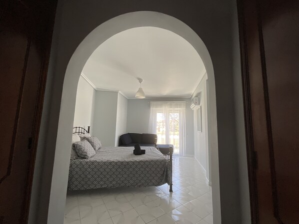 A bedroom with a bed, a chair, and a window.