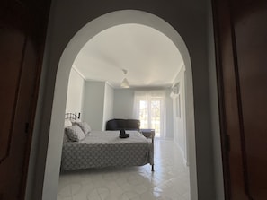 Un dormitorio con cama, una silla y una ventana.
