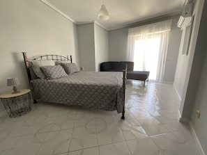 Un dormitorio con cama, mesita de noche, lámpara y ventana con cortinas.