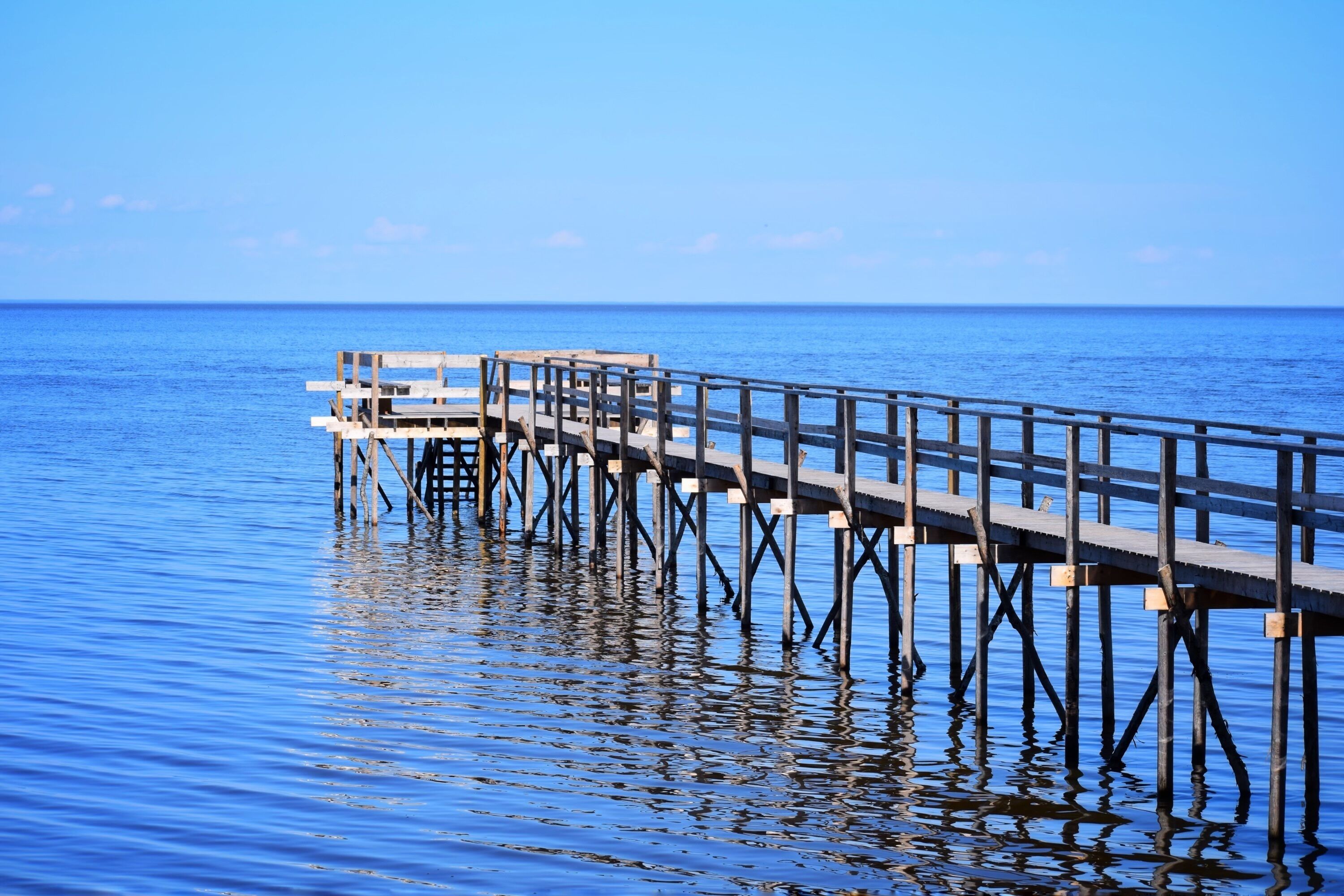 Eine Holzsteg, der sich ins ruhige, blaue Wasser erstreckt.