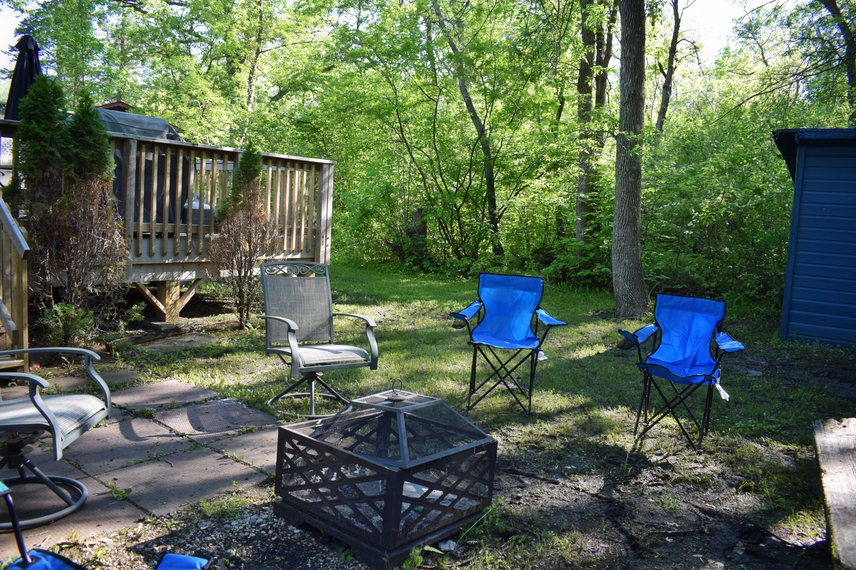 A deck with a chair and a fire pit in a wooded area.