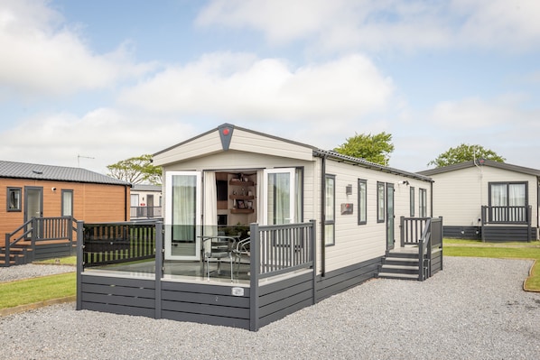 A mobile home with a front porch, a staircase, and a small outdoor seating area.