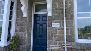 Una casa in pietra con una porta blu, un portico bianco e un'insegna che recita 'HAZELBURY HOUSE'.