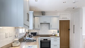 Una cucina moderna con mobili bianchi, forno integrato, microonde e un piano di lavoro in legno.