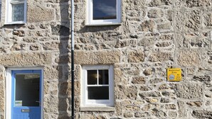 A stone building with a blue door and two windows. There is a yellow sign indicating a restricted zone. - Lower Deck -  a cottage that sleeps 4 guests  in 2 bedrooms (St Ives)