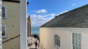 A narrow street with buildings on either side, leading to a waterfront with a boat dock.