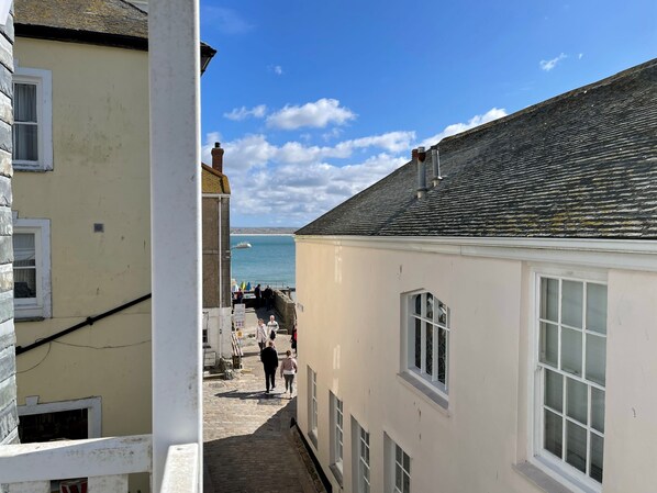A narrow street with buildings on either side, leading to a waterfront with a boat dock. - 1 Sunnyside - an apartment that sleeps 4 guests in 2 bedrooms (St Ives)