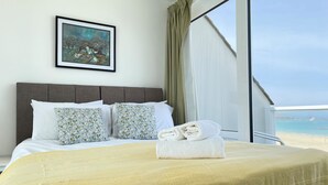 Une chambre d’hôtel avec un lit, un tableau au mur et une vue sur la plage.