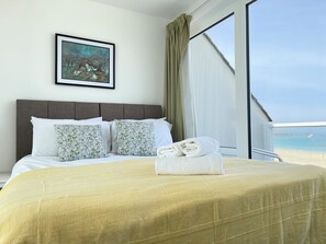 Une chambre d’hôtel avec un lit, un tableau au mur et une vue sur la plage.