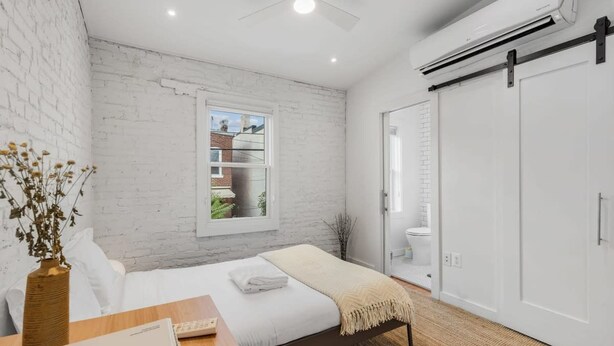 Une chambre à coucher avec un lit, une fenêtre, une armoire et un ventilateur de plafond.