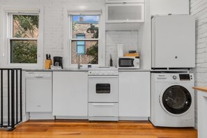Cocina compacta con muebles blancos, lavavajillas, horno, microondas y lavadora.
