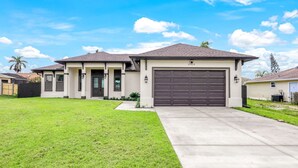 A two-story house with a garage, a well-maintained lawn, and a clear sky.