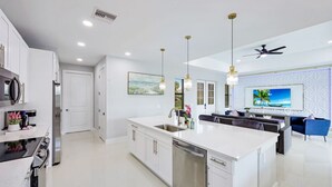 A modern kitchen with white cabinetry, stainless steel appliances, and pendant lighting.